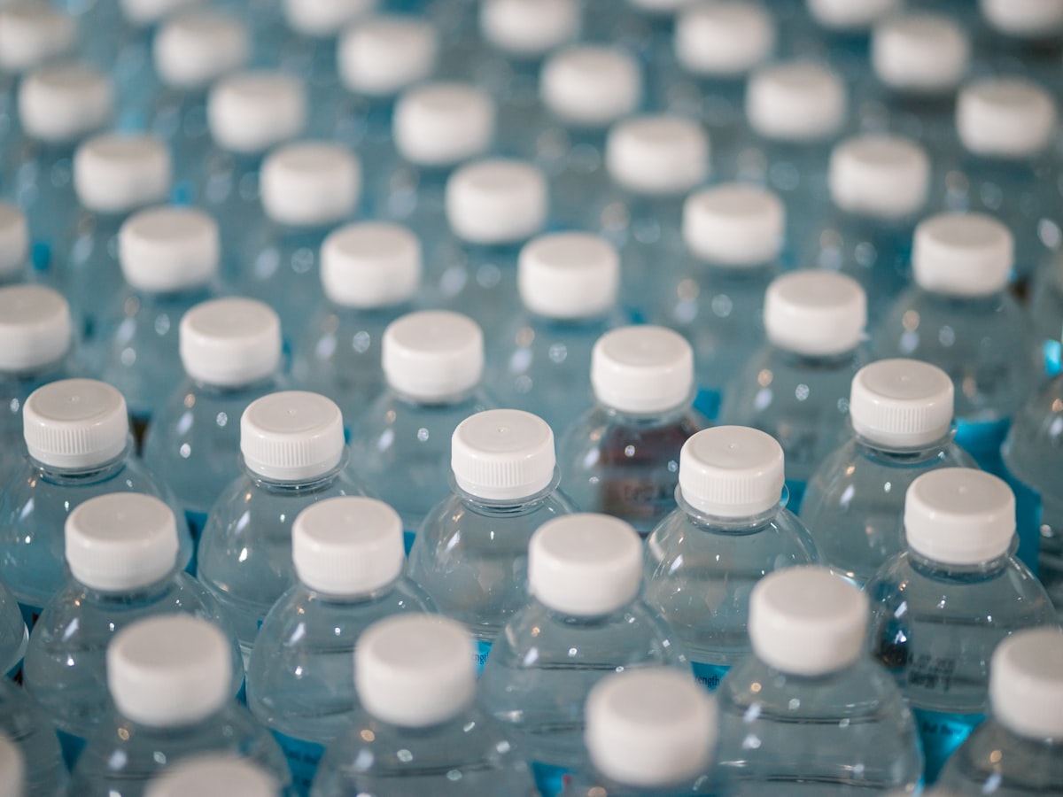 Rows of clear, colorless PET plastic bottles with white caps, the type Korea collects rinsed and label-free as its own separate recycling stream.