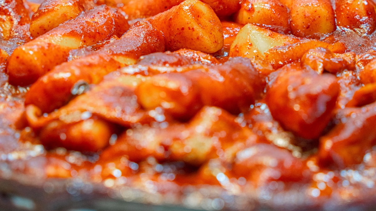 A pan of tteokbokki (Korean spicy rice cakes) simmering in bright red gochujang sauce