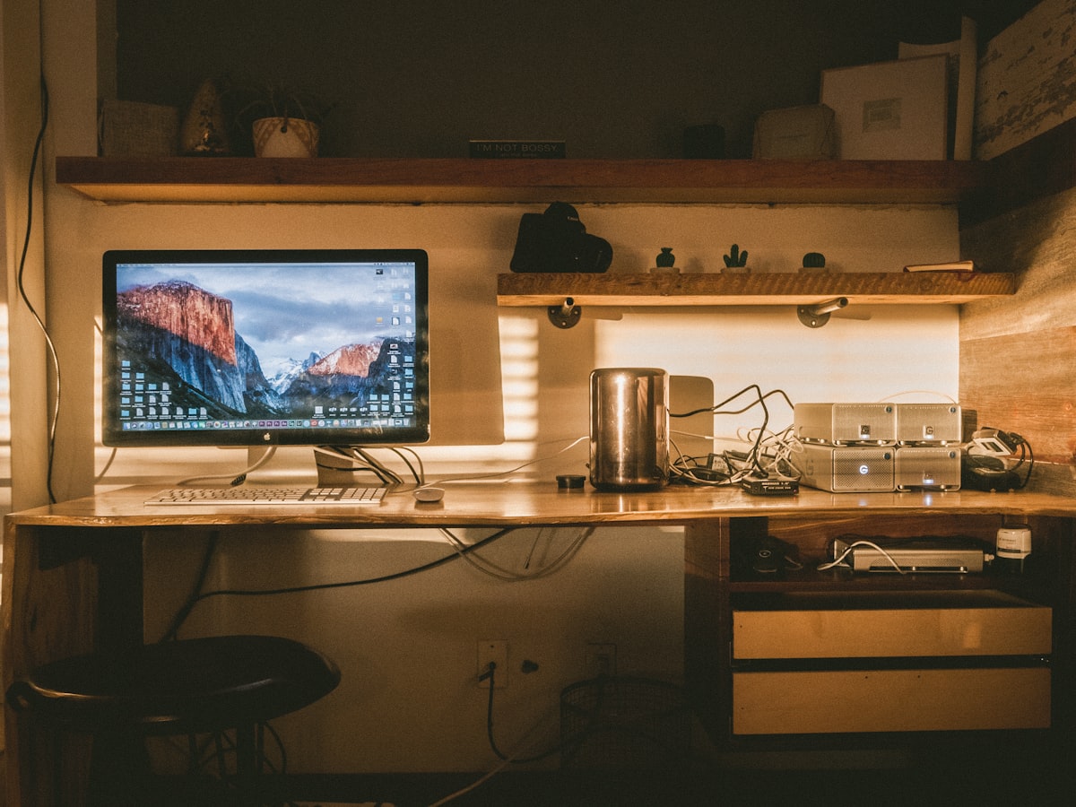 A single computer monitor glowing at a dimly lit desk as the workday winds down