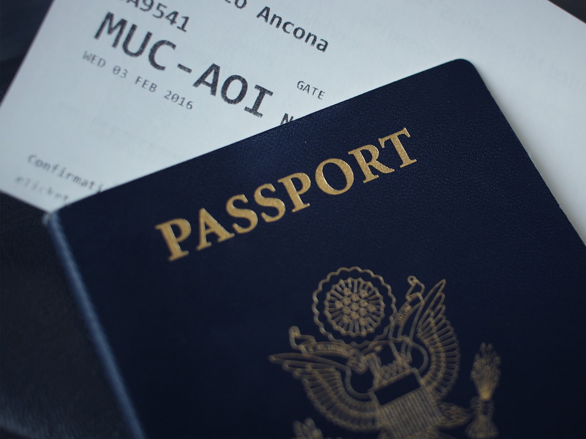 A close-up of a passport booklet resting on top of a printed travel document, the kind of official paperwork a school registration office asks foreign parents to produce