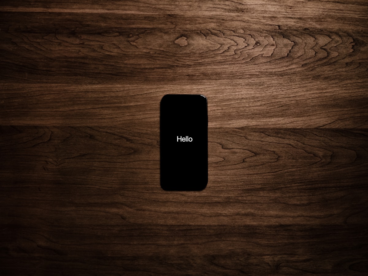 A single smartphone with a dark screen lying face-up on a warm wooden table