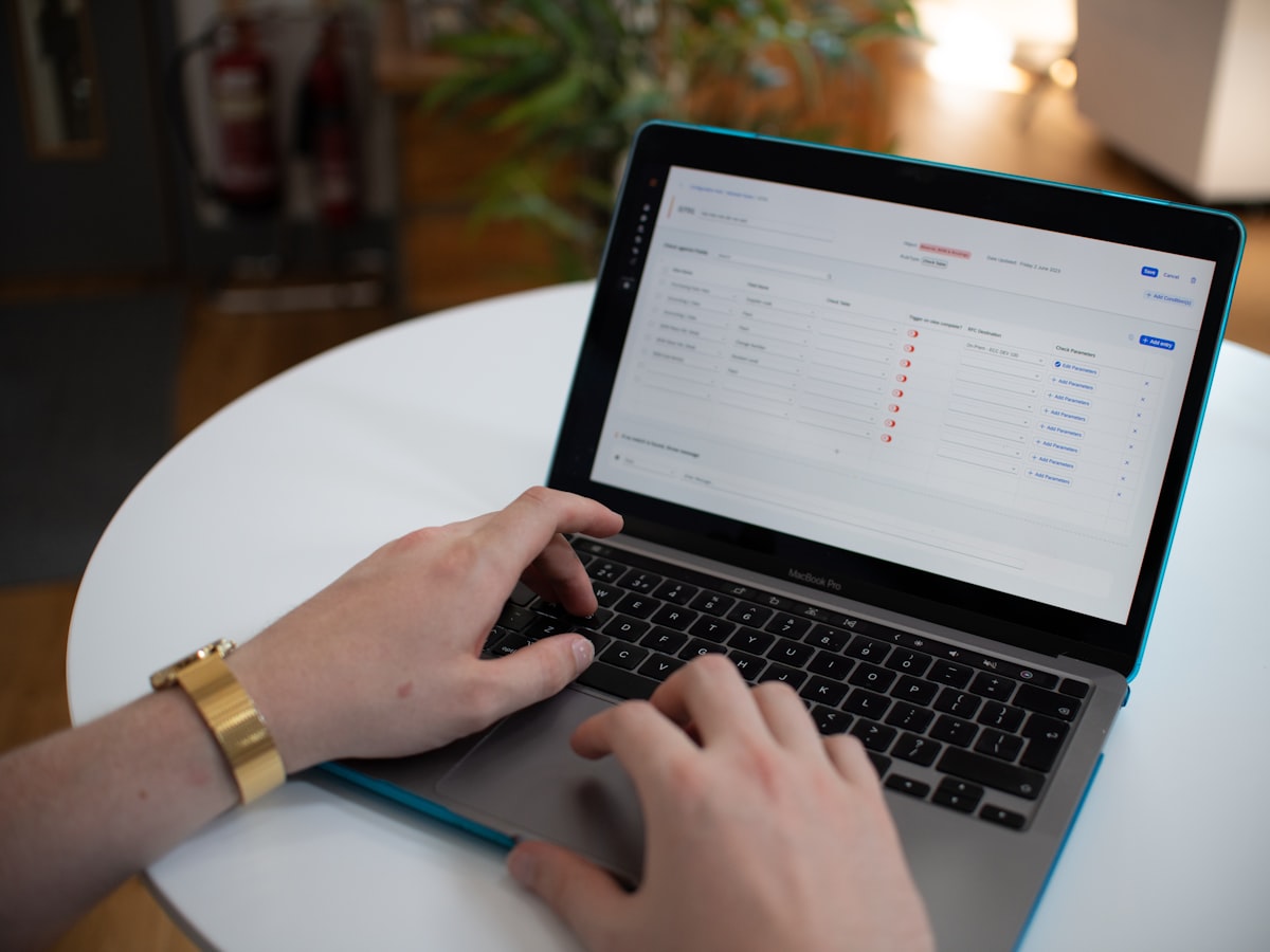 A person's hands typing on a laptop displaying a form with a list of toggled conditions, similar to reviewing an eligibility checklist online