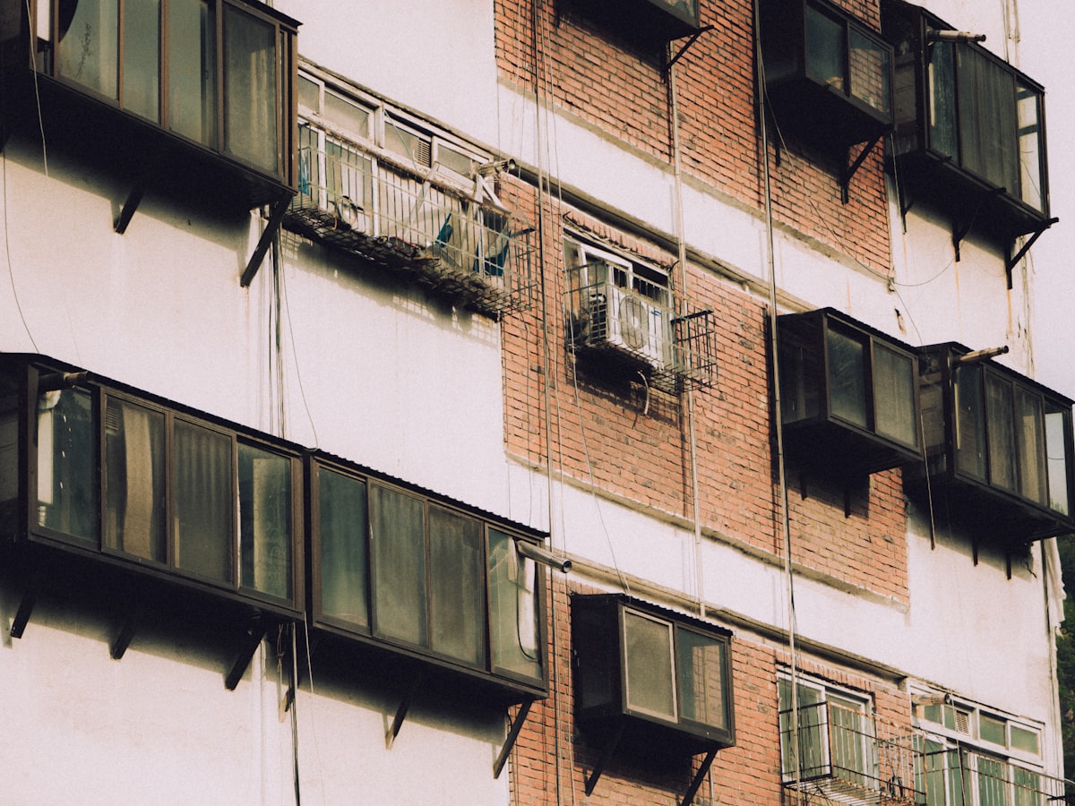 Rows of enclosed balconies on an older apartment building facade in Seoul, no flags visible