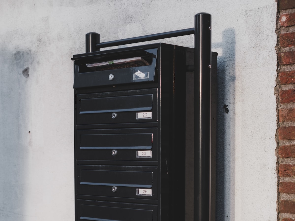 A wall-mounted apartment mailbox cluster with numbered mail slots
