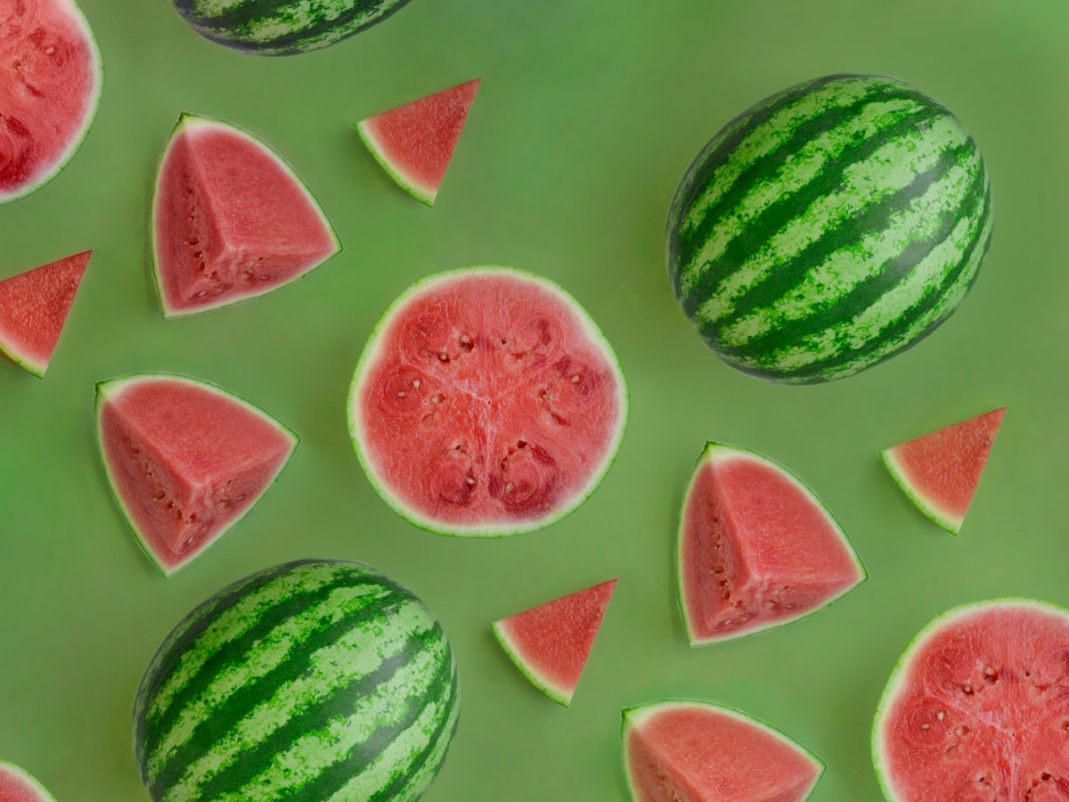 Whole watermelons and triangular watermelon wedges scattered side by side, showing whole vs. cut portions