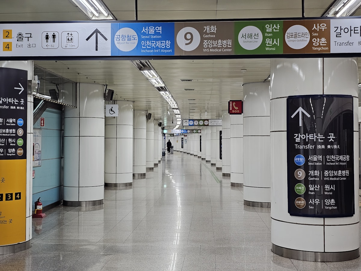 A Seoul subway transfer corridor lined with illuminated route signage and departure boards.