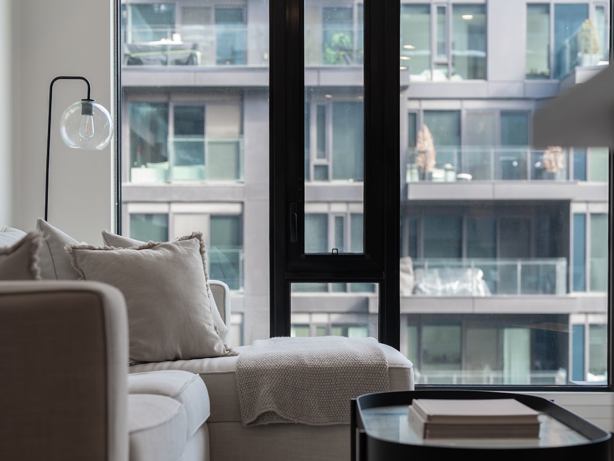 A modern apartment living room with a large window overlooking a dense high-rise city skyline