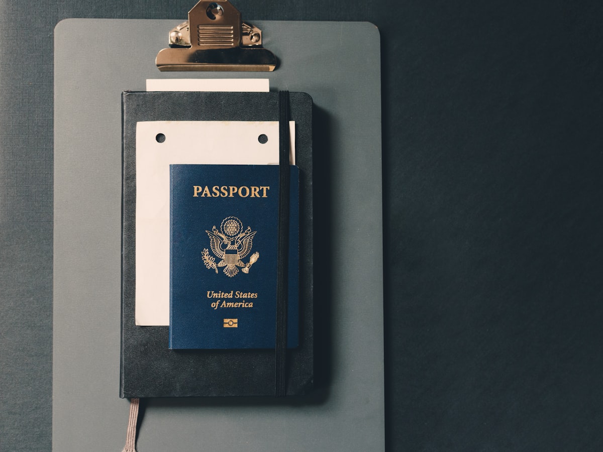 A passport resting on a notebook and clipboard, representing the identity and paperwork foreign buyers must submit