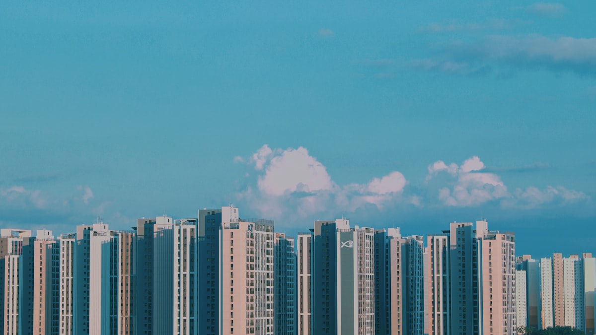 Row of high-rise Korean apartment towers against a blue sky with scattered clouds