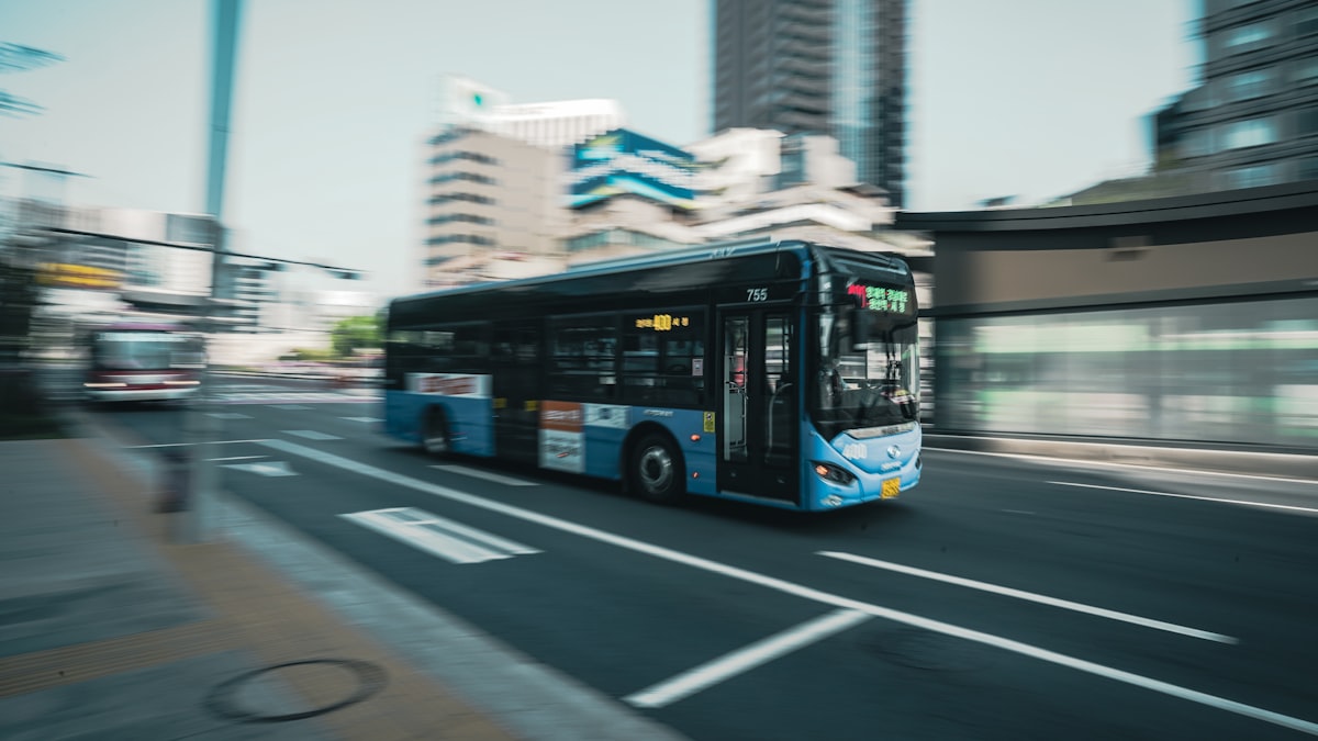 A blue Seoul city bus in motion on a downtown street, panning motion-blur shot with high-rise buildings in the background