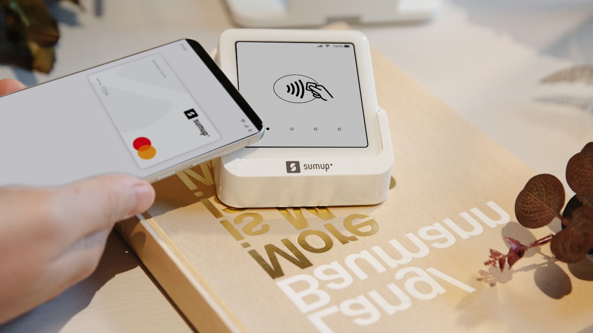 A smartphone tapping a contactless payment card reader