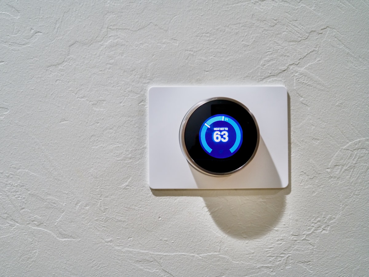 A white wall-mounted digital thermostat display reading 'Heat set to 63'