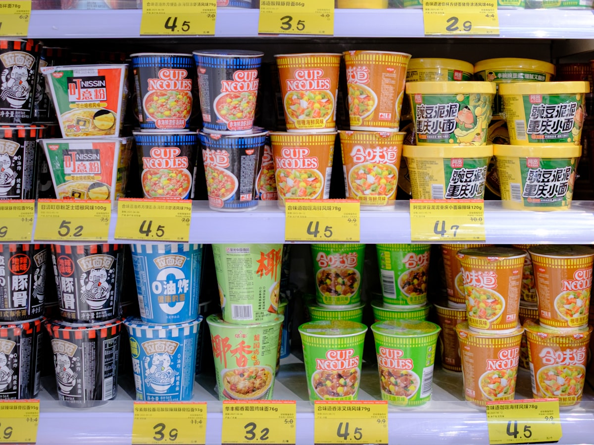 A wall of cup noodle flavors and price tags on a store shelf