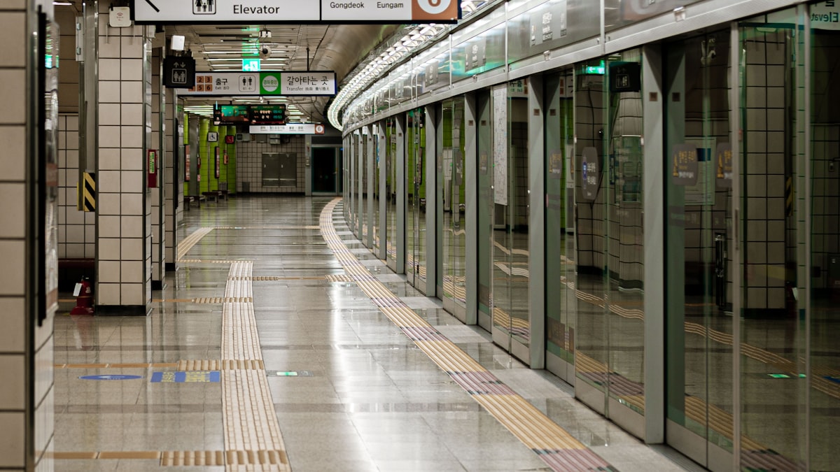 Empty Seoul subway platform with closed platform screen doors and Korean transfer signs overhead