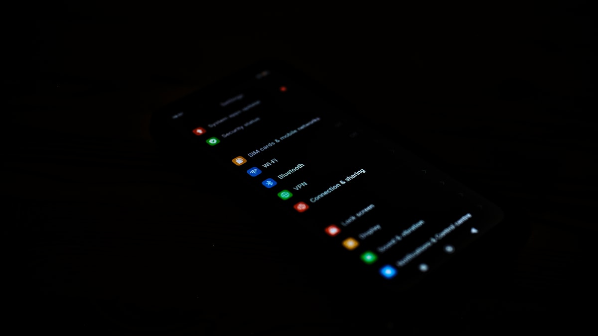 A smartphone lying face-up in a dark room, its screen glowing with a security and connection settings menu