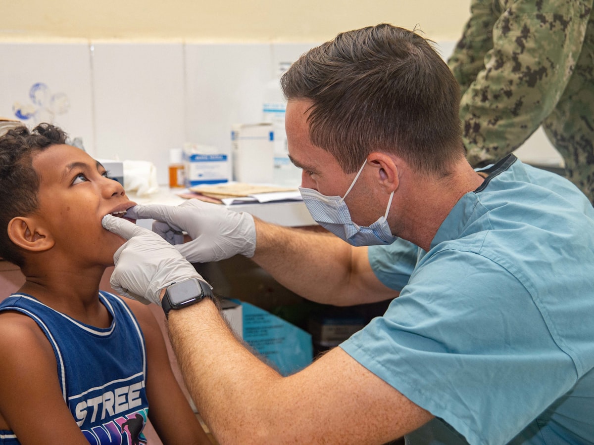 A dental professional examining a young boy's teeth during a pediatric dental checkup