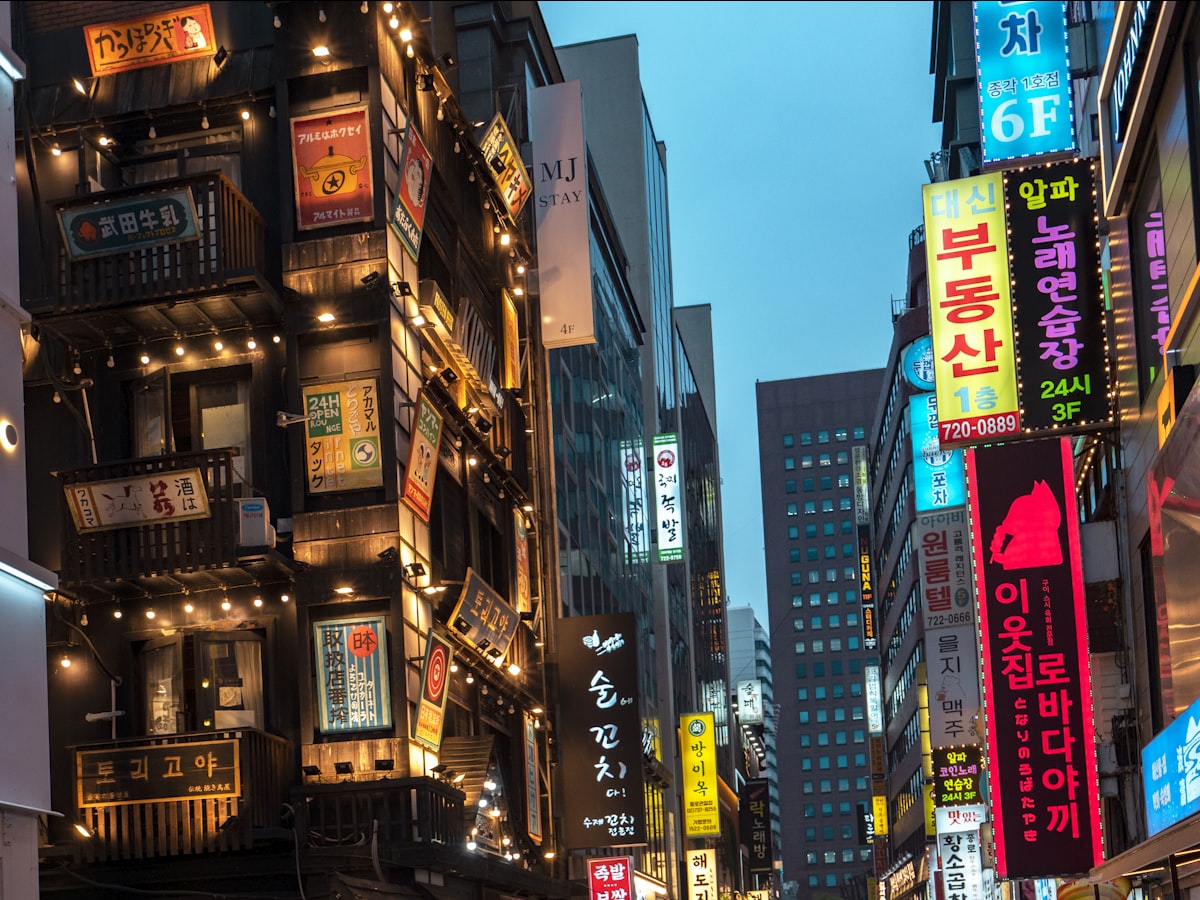 Neon shop signage on a busy Seoul commercial street at dusk