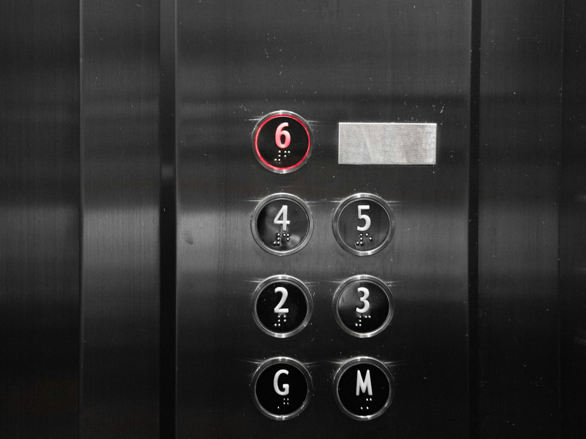 Close-up of a modern, minimalist black elevator button panel with a plain number 4 button printed clearly among 2, 3, 5, 6, G, and M